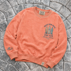 Coral-colored crewneck with 'Grace Upon Grace Surf Club' design on a stone surface