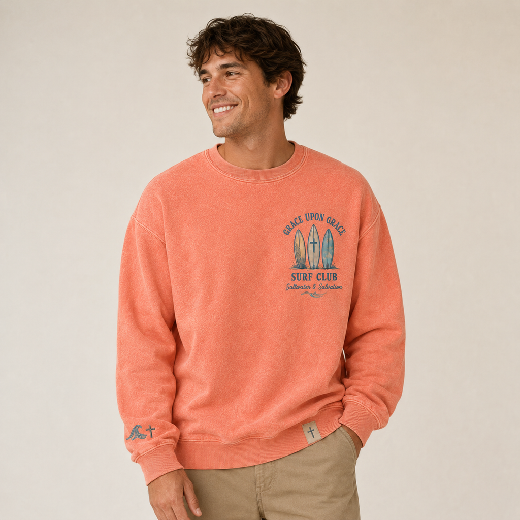 Man wearing a coral crewneck with a graphic design on a beige background