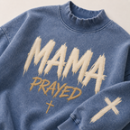 Blue sweatshirt with 'MAMA PRAYED' text in beige on a light background