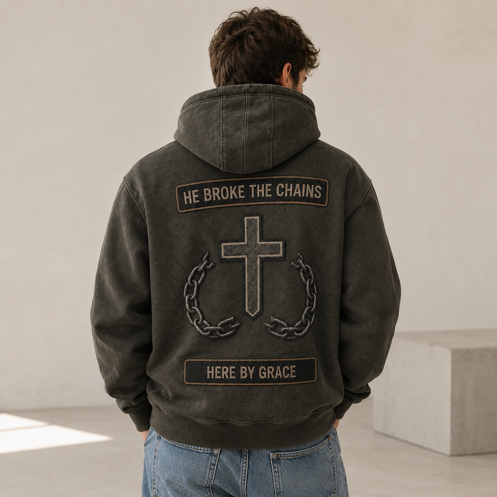 Man wearing a dark jacket with a cross and text design on the back, standing against a plain background.