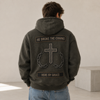 Man wearing a dark jacket with a cross and text design on the back, standing against a plain background.