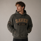Man wearing a dark gray hoodie with 'SAVED BY JESUS' text on a neutral background