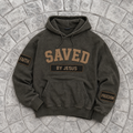 Dark green/black hoodie with 'SAVED BY JESUS' text on a stone surface